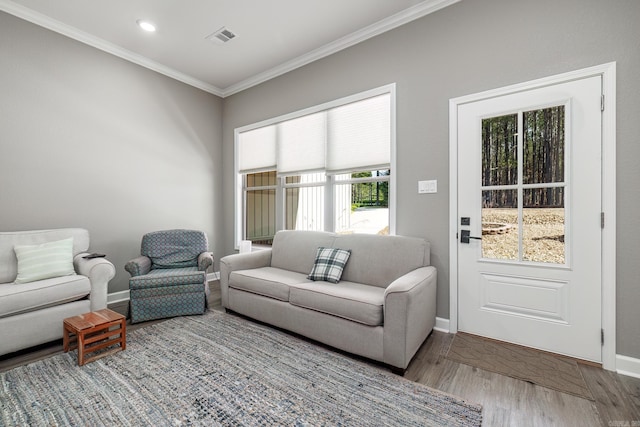 living room featuring baseboards, visible vents, crown molding, and wood finished floors