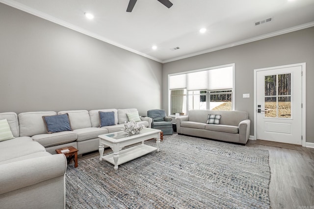 living room featuring ornamental molding, visible vents, baseboards, and wood finished floors