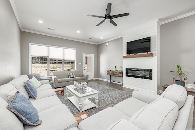 living room with a large fireplace, recessed lighting, wood finished floors, and crown molding