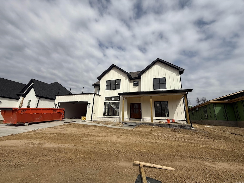 modern inspired farmhouse featuring board and batten siding, covered porch, driveway, and an attached garage