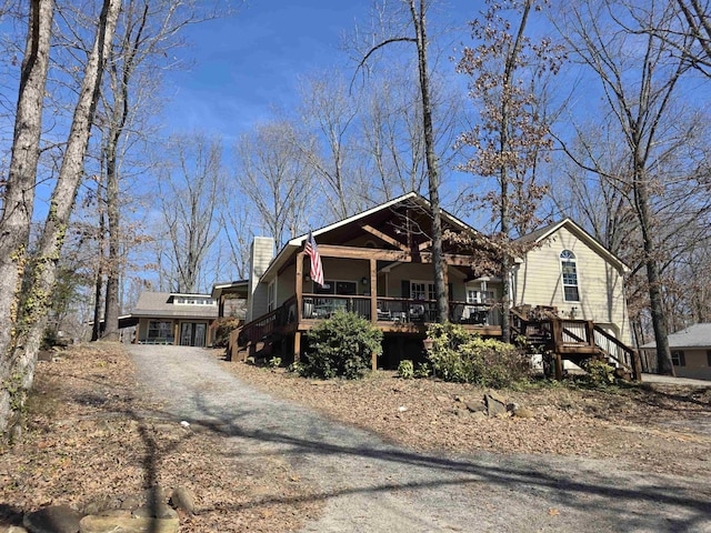 view of front of property featuring dirt driveway, a chimney, and stairway