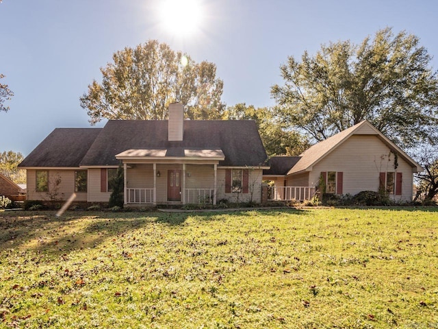 back of property featuring covered porch, a chimney, and a yard