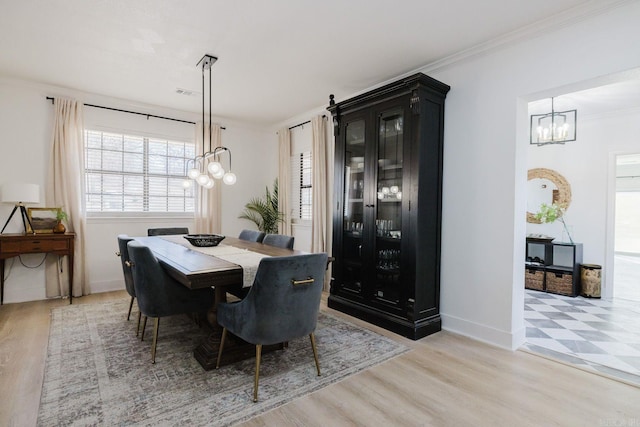 dining space with ornamental molding, a chandelier, baseboards, and light wood finished floors