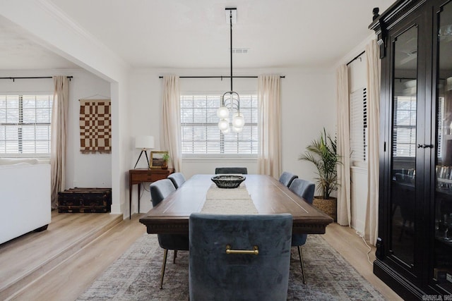 dining room featuring ornamental molding, light wood finished floors, a chandelier, and visible vents