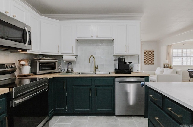 kitchen with a sink, white cabinets, light countertops, appliances with stainless steel finishes, and backsplash