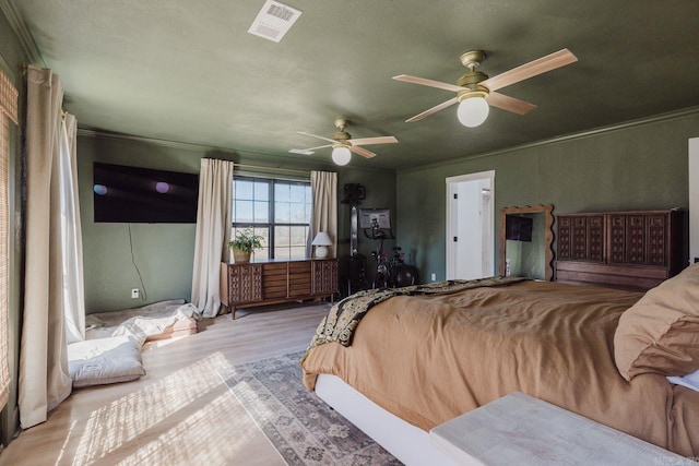 bedroom with a ceiling fan, light wood-type flooring, and visible vents