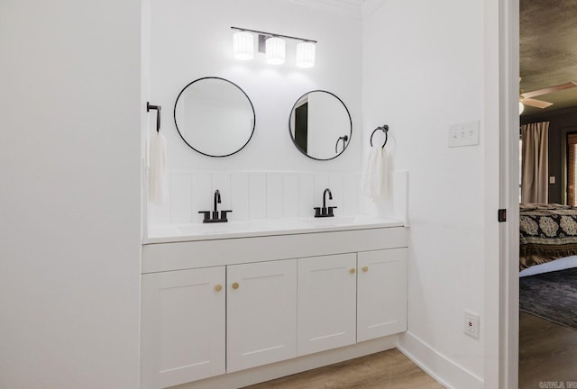 ensuite bathroom featuring double vanity, ensuite bathroom, a ceiling fan, a sink, and wood finished floors