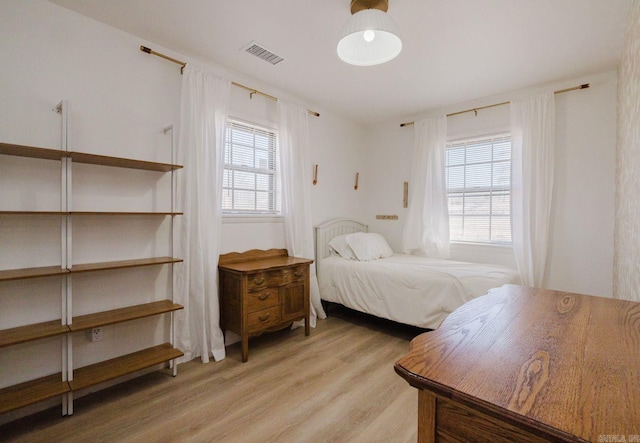 bedroom with light wood finished floors, multiple windows, and visible vents