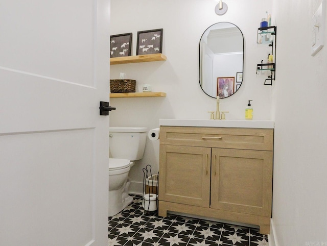 half bath featuring baseboards, vanity, toilet, and tile patterned floors