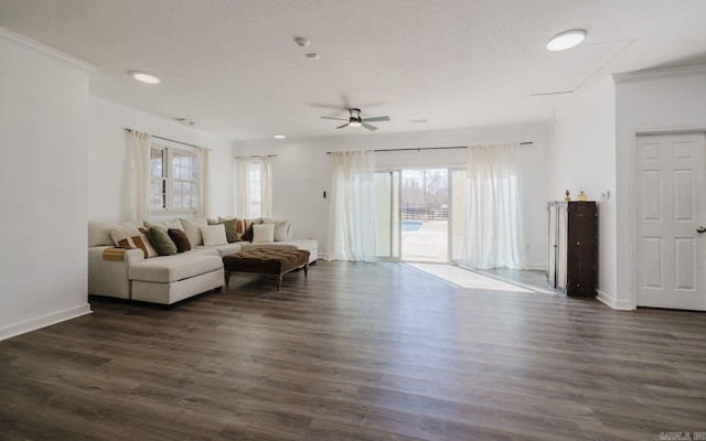 living room with a textured ceiling, ornamental molding, dark wood-style flooring, and baseboards