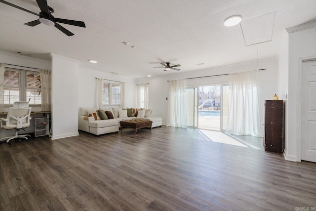 living room featuring dark wood-style floors, attic access, ornamental molding, a textured ceiling, and baseboards