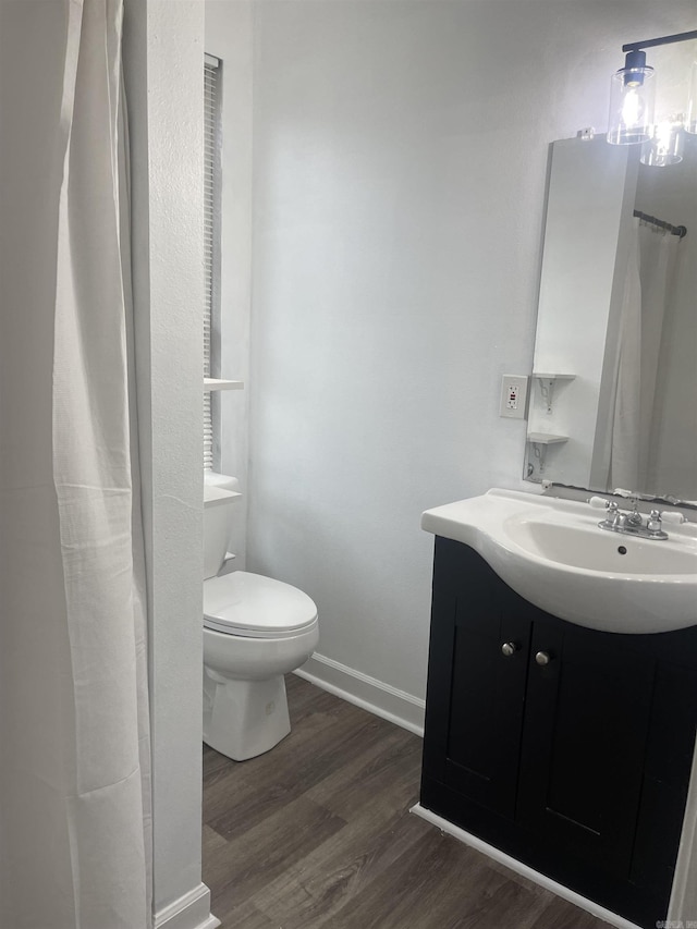 full bathroom featuring toilet, baseboards, wood finished floors, and vanity