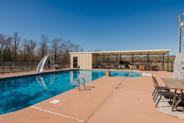 view of swimming pool featuring a fenced in pool, a water slide, fence, and a patio