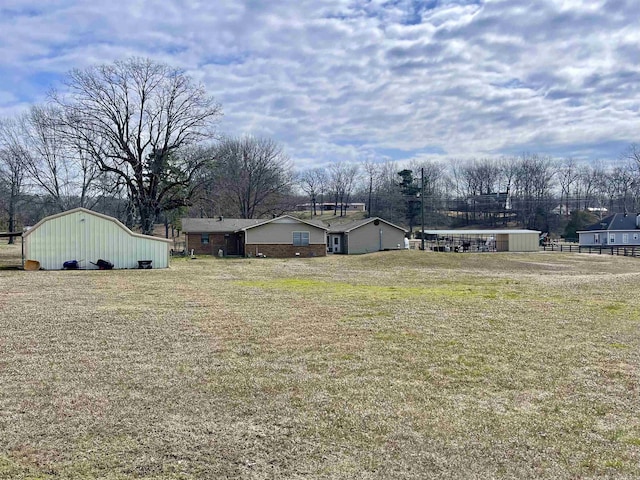 view of yard featuring a garage, a barn, fence, and an outdoor structure