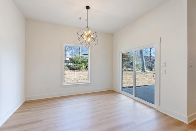 unfurnished dining area with a healthy amount of sunlight, light wood finished floors, and a notable chandelier