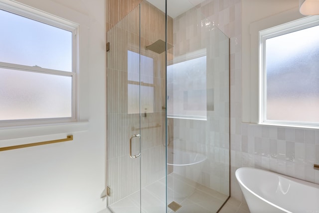 full bath featuring a freestanding tub, tile walls, and a shower stall