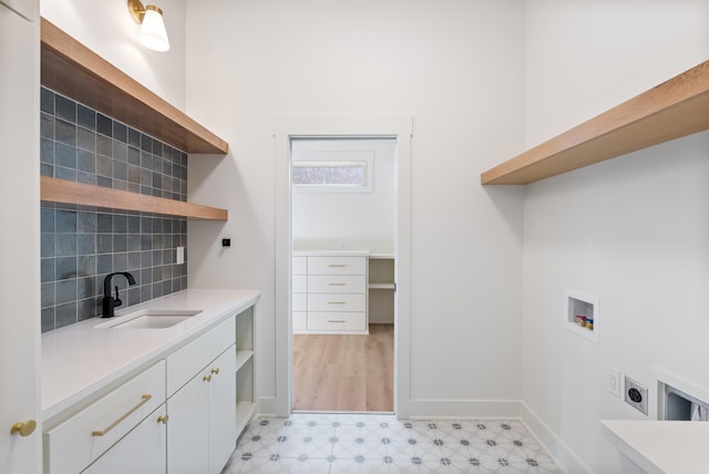 clothes washing area with cabinet space, hookup for a washing machine, hookup for an electric dryer, light floors, and a sink