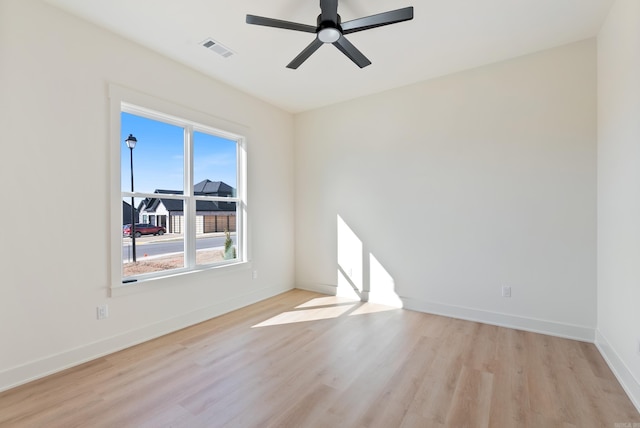 spare room with ceiling fan, light wood finished floors, visible vents, and baseboards