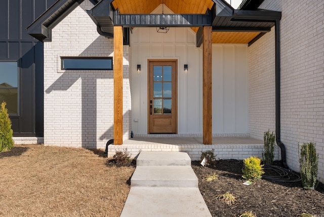 view of exterior entry featuring covered porch and board and batten siding