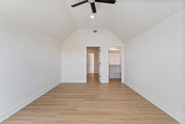 unfurnished bedroom with lofted ceiling, visible vents, baseboards, a spacious closet, and light wood-type flooring