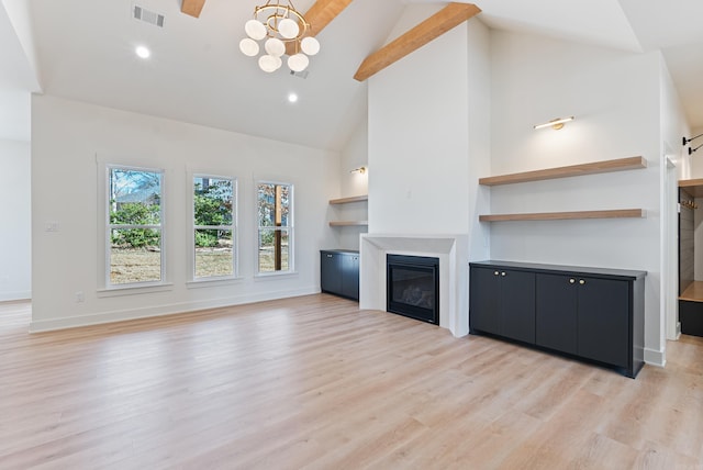 unfurnished living room with visible vents, light wood-style flooring, an inviting chandelier, a glass covered fireplace, and baseboards