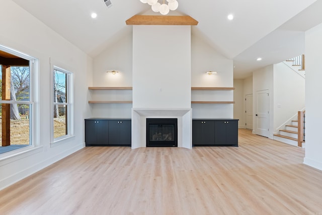 unfurnished living room with recessed lighting, light wood-style floors, a glass covered fireplace, baseboards, and stairs