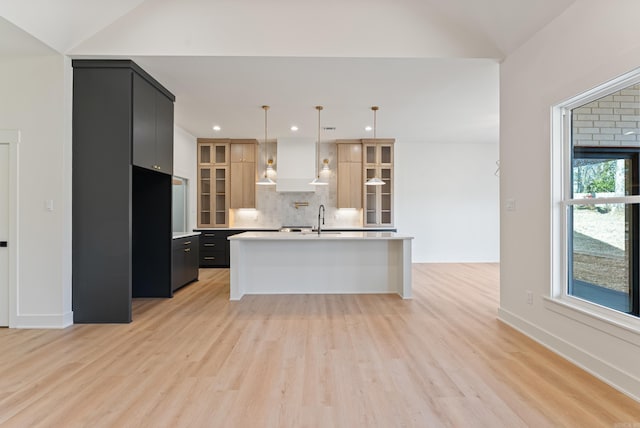 kitchen featuring light wood finished floors, decorative backsplash, light countertops, and dark cabinets