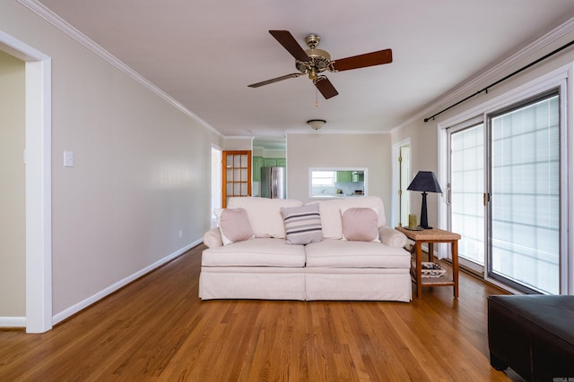 living area featuring baseboards, ceiling fan, wood finished floors, and crown molding