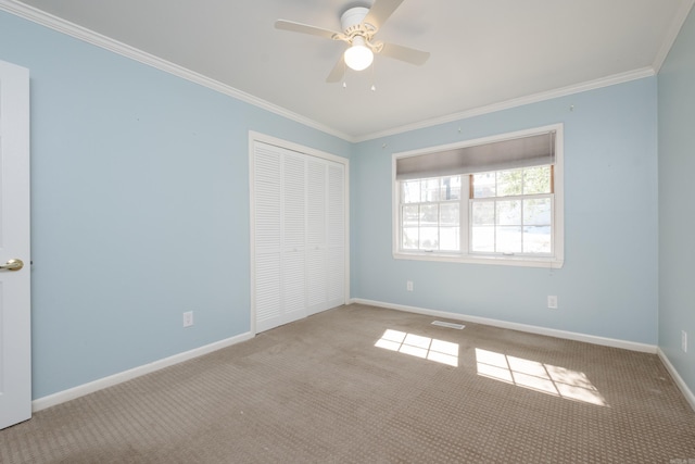 unfurnished bedroom with baseboards, visible vents, ornamental molding, carpet flooring, and a closet