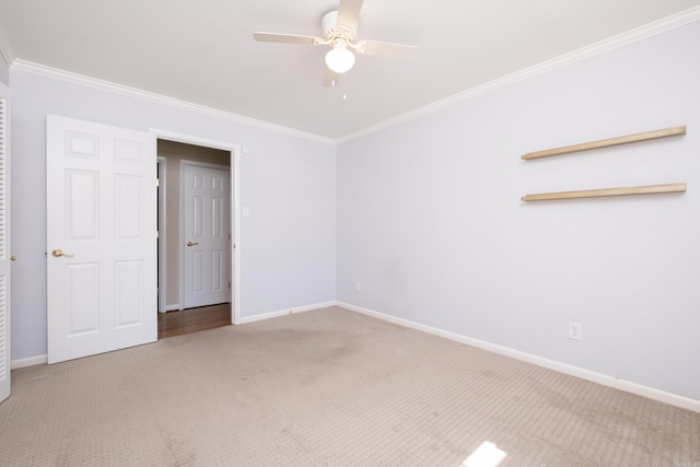 carpeted empty room featuring ceiling fan, ornamental molding, and baseboards