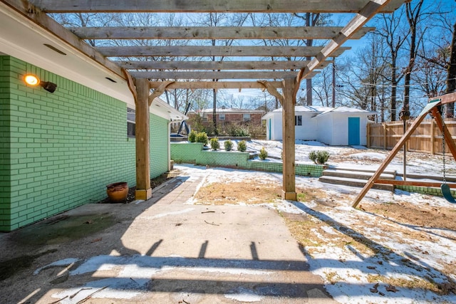 yard layered in snow with an outbuilding, fence, and a pergola