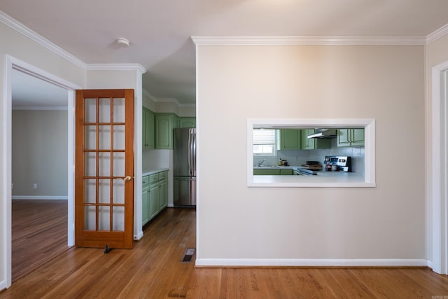 corridor featuring a sink, ornamental molding, wood finished floors, and visible vents