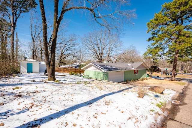 view of yard with a garage, an outbuilding, fence, and a storage shed