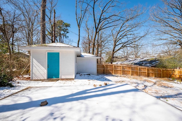 snow covered structure featuring an outbuilding and fence