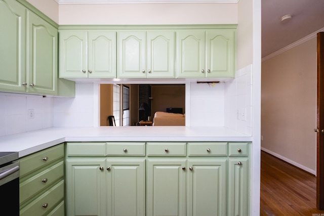 kitchen with light countertops, green cabinetry, crown molding, and decorative backsplash