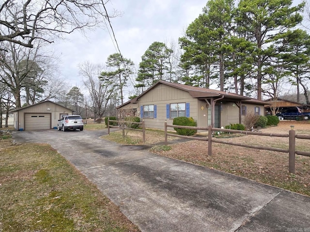 view of front facade featuring an outbuilding, driveway, a fenced front yard, and a garage