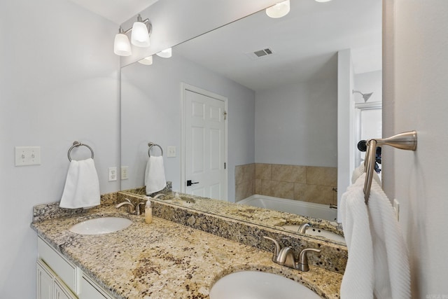 bathroom with visible vents, a sink, a garden tub, and double vanity