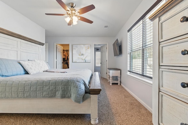 carpeted bedroom featuring ceiling fan, a spacious closet, visible vents, and baseboards