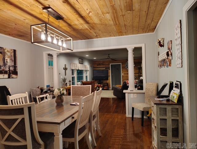 dining room featuring decorative columns, a ceiling fan, wood ceiling, wood finished floors, and crown molding