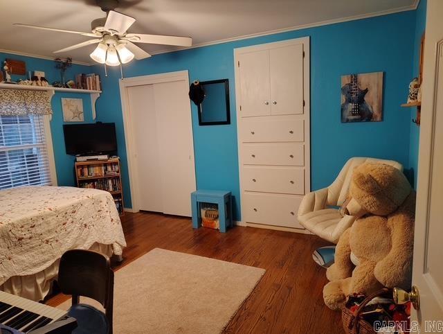 bedroom featuring ornamental molding, dark wood-style flooring, a closet, and a ceiling fan