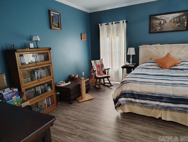 bedroom featuring ornamental molding and wood finished floors