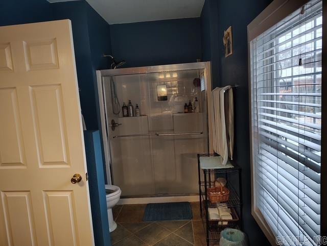 bathroom with toilet, a shower stall, and tile patterned floors