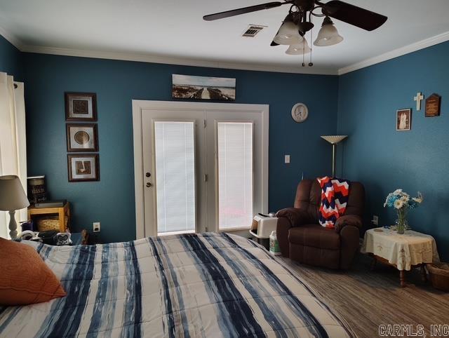 bedroom featuring ornamental molding, wood finished floors, visible vents, and a ceiling fan