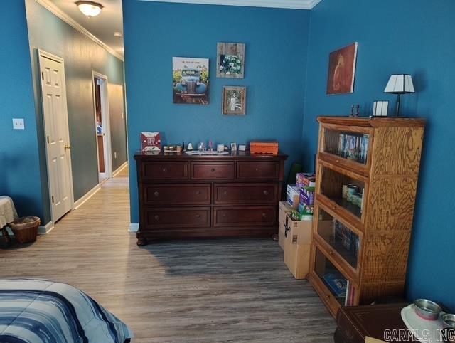 bedroom with crown molding, baseboards, and wood finished floors