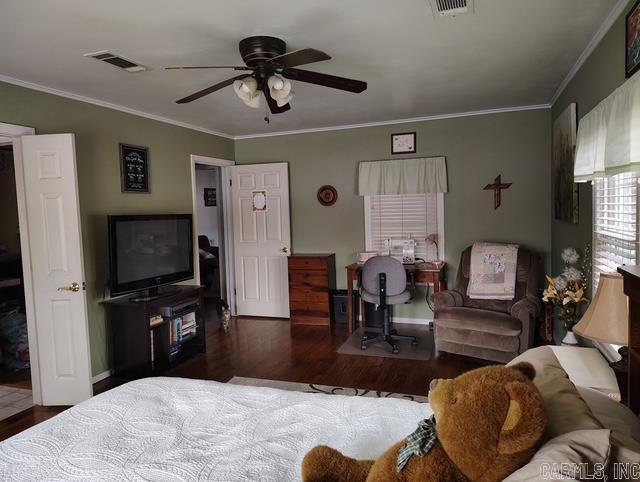 living area with visible vents, crown molding, and wood finished floors