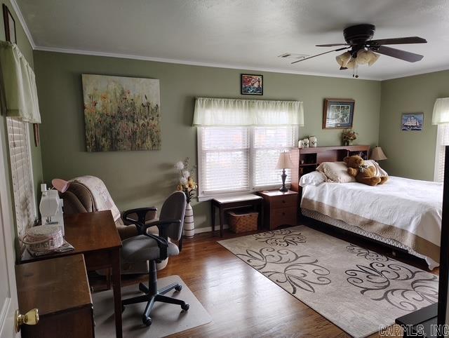 bedroom featuring ceiling fan, crown molding, and wood finished floors