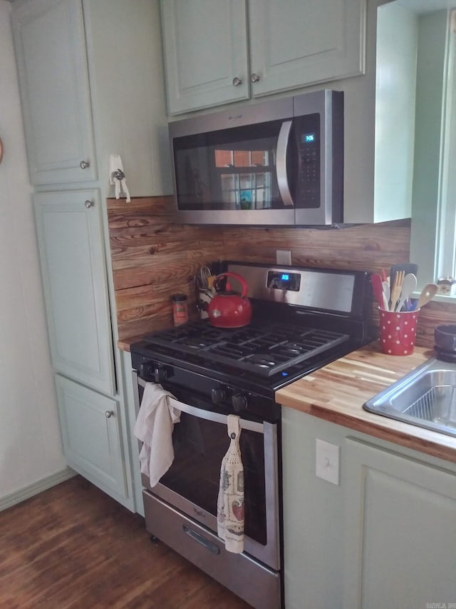 kitchen featuring wooden counters, appliances with stainless steel finishes, dark wood-type flooring, and white cabinetry