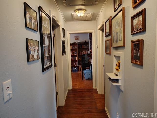 corridor with dark wood-style floors, attic access, and crown molding