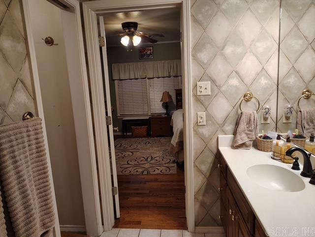 bathroom with ceiling fan, tile patterned flooring, vanity, and tile walls