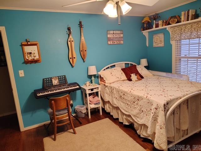 bedroom with wood finished floors, a ceiling fan, and crown molding